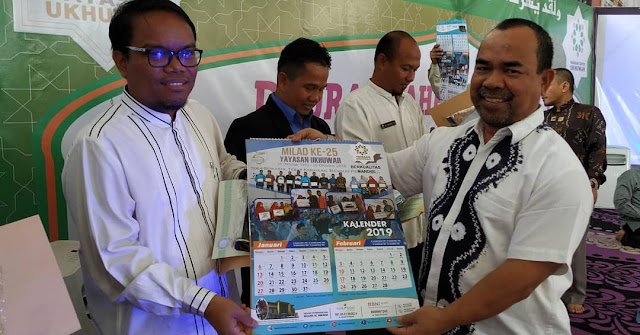 Hilmi Hasan menyerahkan sertifikat plakat dan kalender kepada kepala SMAIT Ukhuwah Rachmansyah